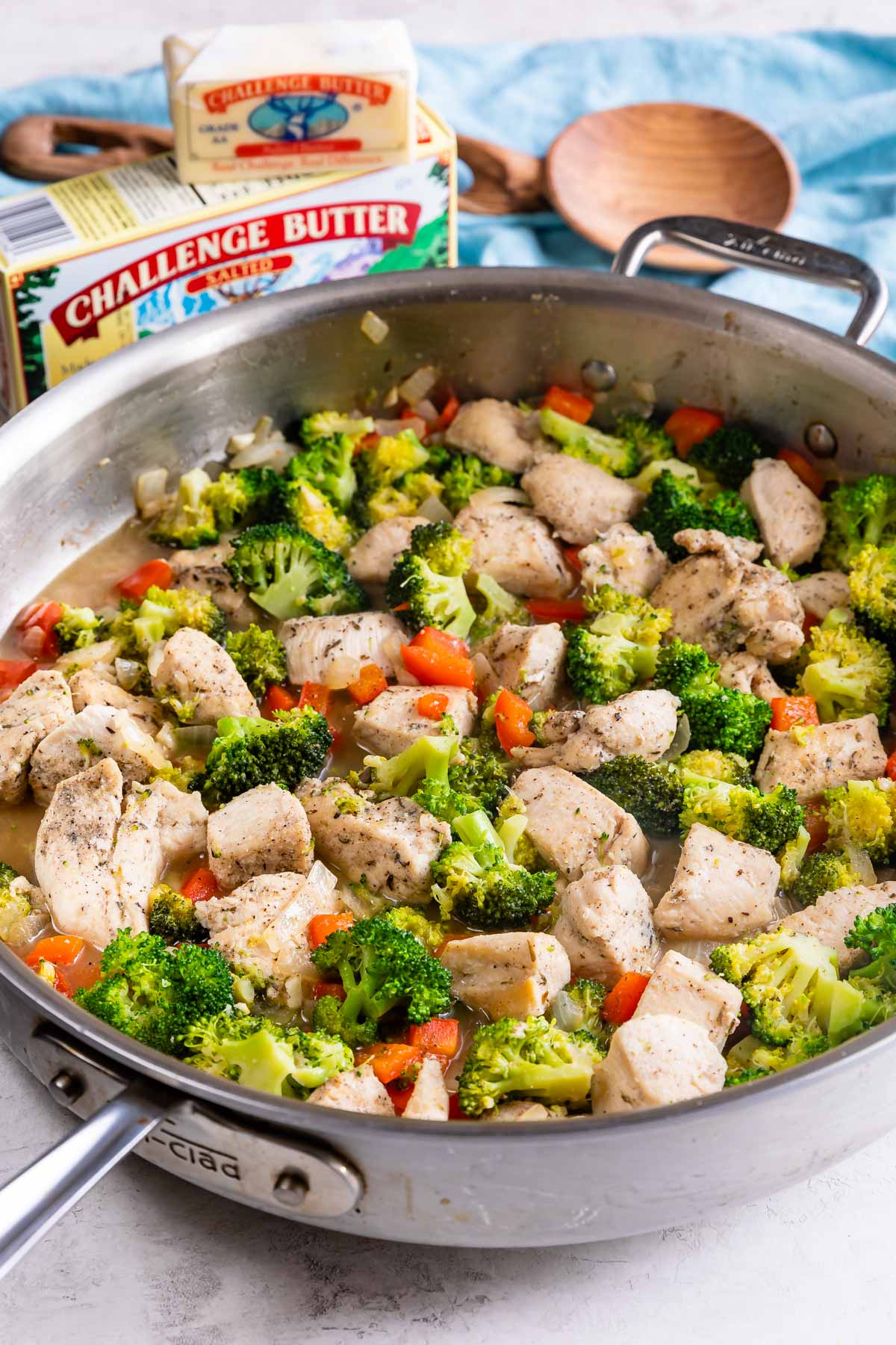 garlic butter chicken and vegetables in skillet with butter behind