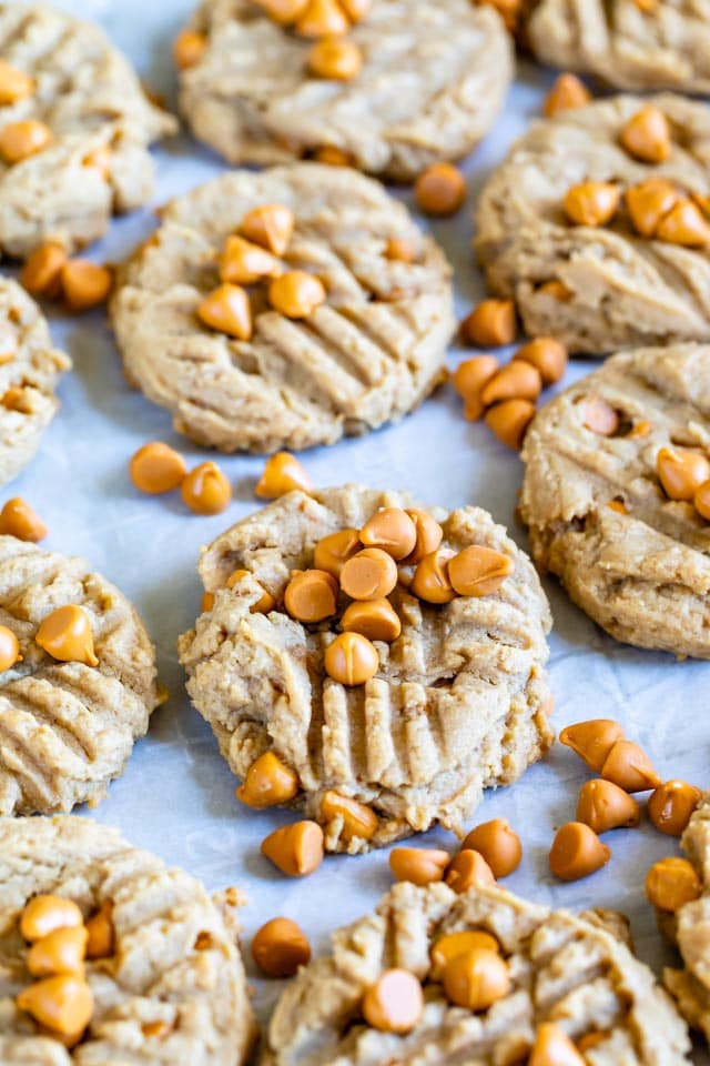 Peanut butter butterscotch cookies on parchment paper with extra butterscotch chips