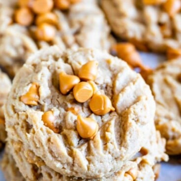 Peanut butter butterscotch cookies stacked on eachother with more surrounding them and recipe title on top of image