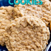 Three peanut butter oatmeal cookies on a royal blue plate next to a spoonful of peanut butter with recipe title on top of image