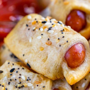 Close up of everything pigs in a blanket stacked on eachother on a plate with recipe title on top of image
