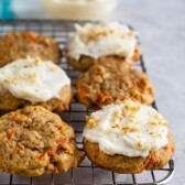 Carrot cake cookies on metal cooling rack, some with frosting on top