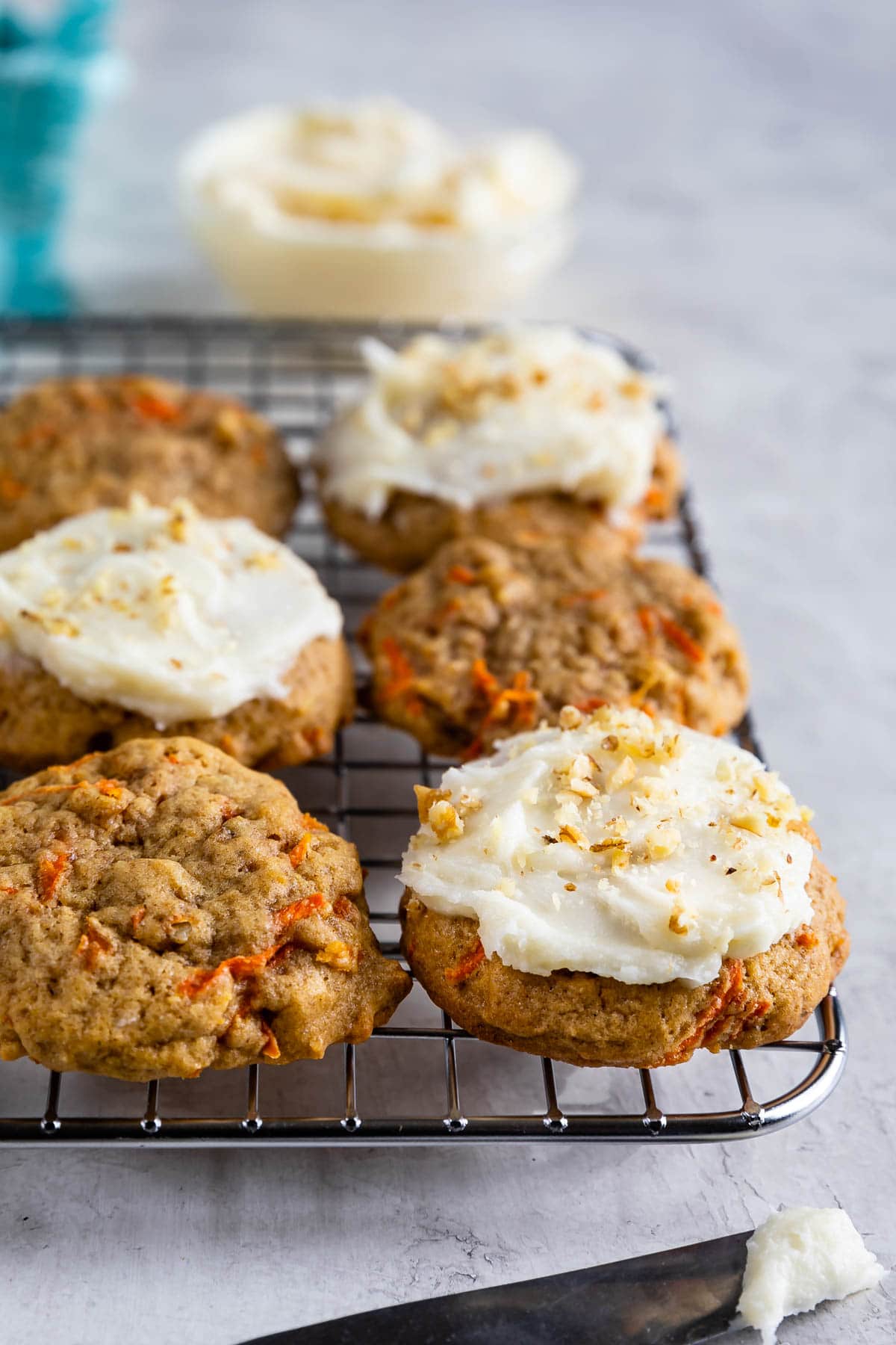 Carrot cake cookies on metal cooling rack, some with frosting on top