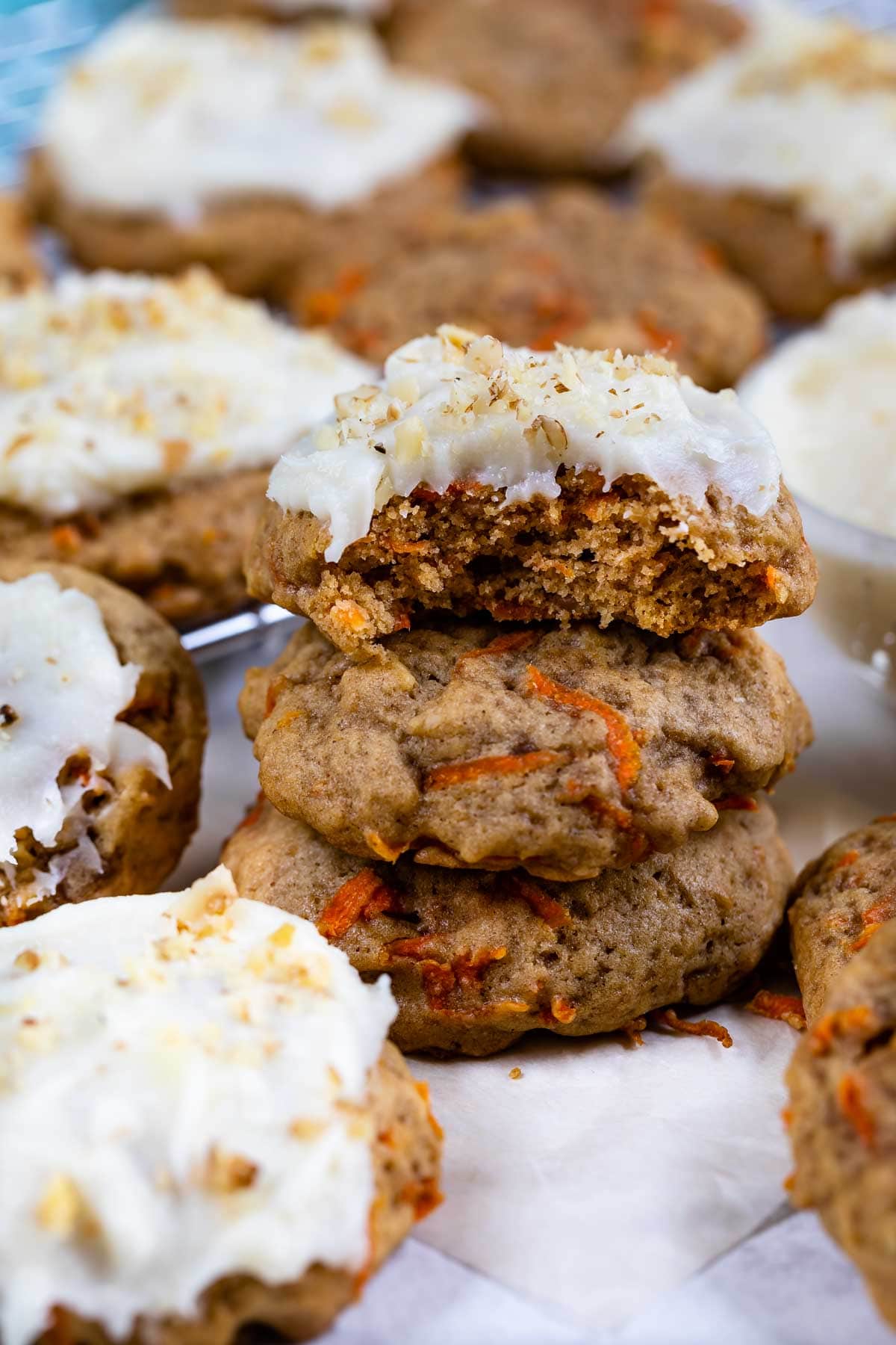 Carrot cake cookies stacked on eachother with top one covered in cream cheese frosting and bite missing