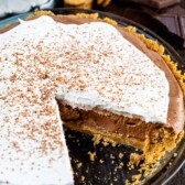 Chocolate cream pie in a glass pie dish with one slice missing