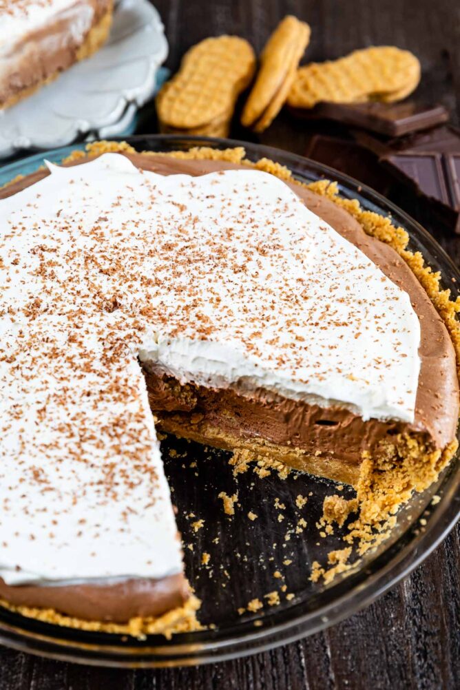 Chocolate cream pie in a glass pie dish with one slice missing