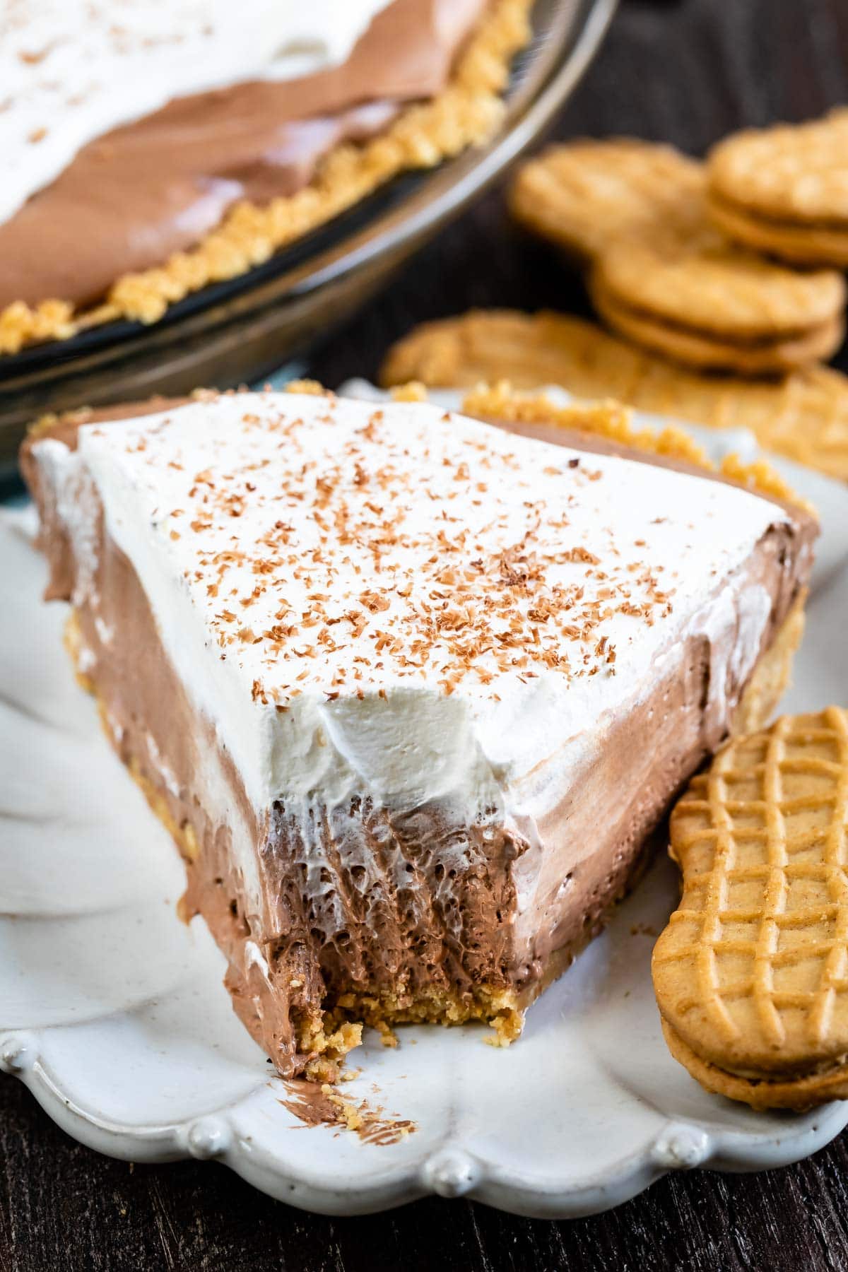 Close up of one slice of chocolate cream pie on a plate with one bite missing