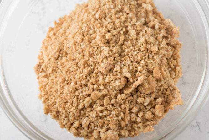 Overhead shot of crushed peanut butter cookies in a clear mixing bowl