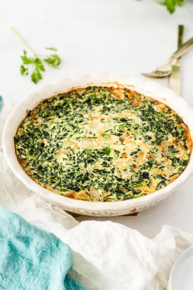 Spinach crustless quiche in a white serving dish after being cooked
