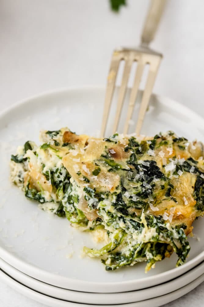 One slice of crustless quiche on a white plate with fork