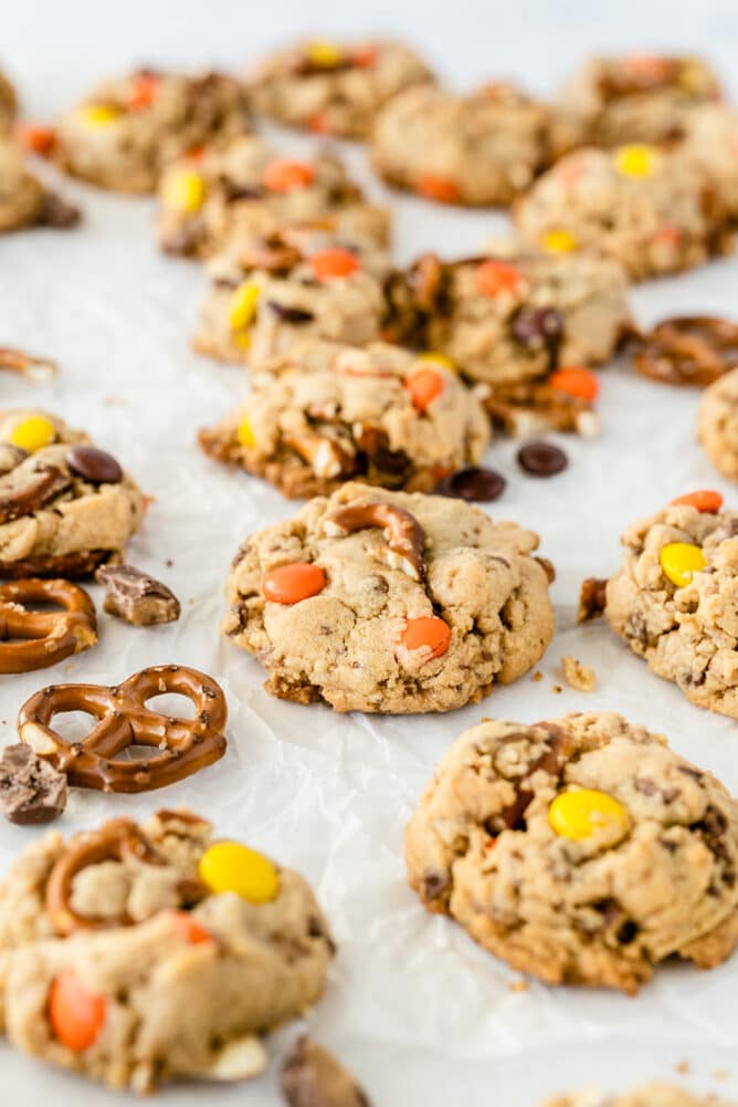 Lots of toffee pretzel peanut butter cookies on parchment paper