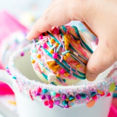 Hand placing one white hot chocolate bomb inside a mug