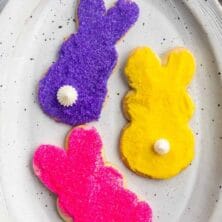 Overhead shot of three decorated bunny cookies on a white serving plate with recipe title on top of image