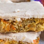 Stack of two carrot cake blondies on parchment paper with recipe title on top of image