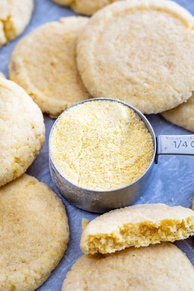 Overhead view of cornmeal cookies with a stainless steel measuring cup full of cornmeal