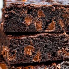 Stack of dark chocolate brownies with chocolate chips around them and recipe title on top of image