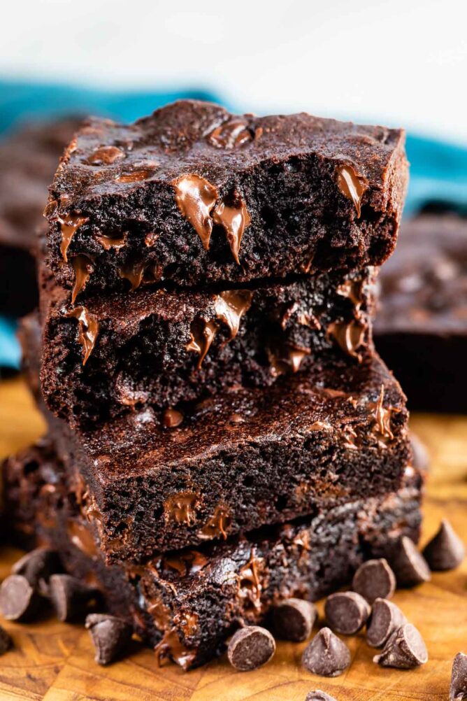 Large, high stack of dark chocolate brownies with chocolate chips around them