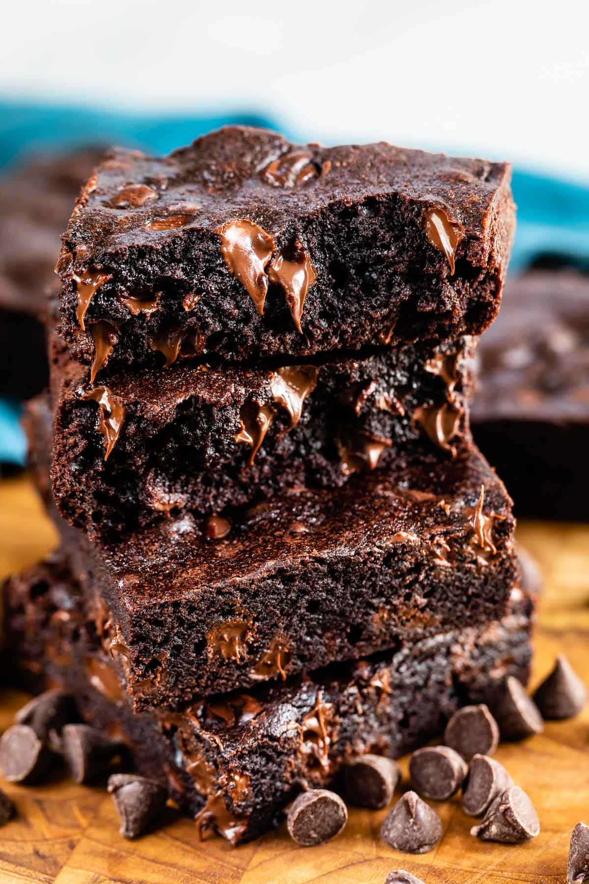 Large, high stack of dark chocolate brownies with chocolate chips around them