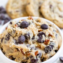 Close up shot of edible cookie dough with baked cookies in background