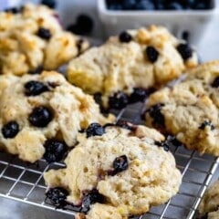 close up of blueberry biscuit on rack with blueberries behind