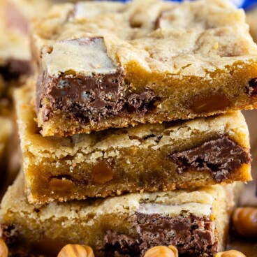 Stack of caramel crunch blondies with crunch candy bars next to it