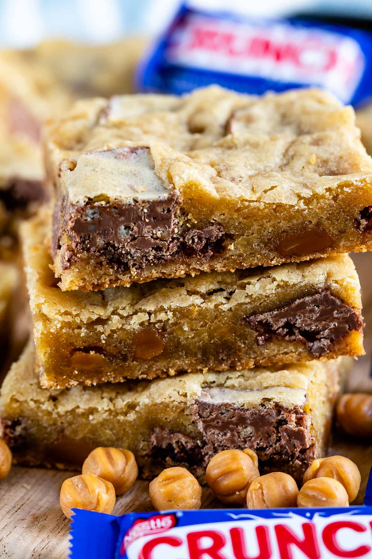 Stack of caramel crunch blondies with crunch candy bars next to it