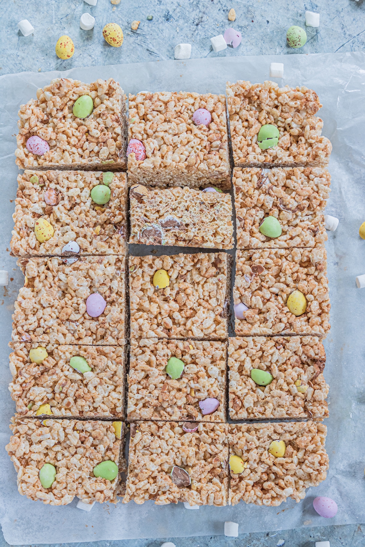 Overhead shot of Easter rice krispie treats cut into squares on parchment paper