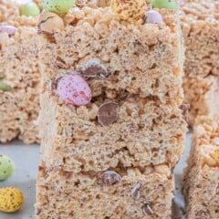 Three Easter rice krispie treats stacked on eachother with more chocolate egg candies around them