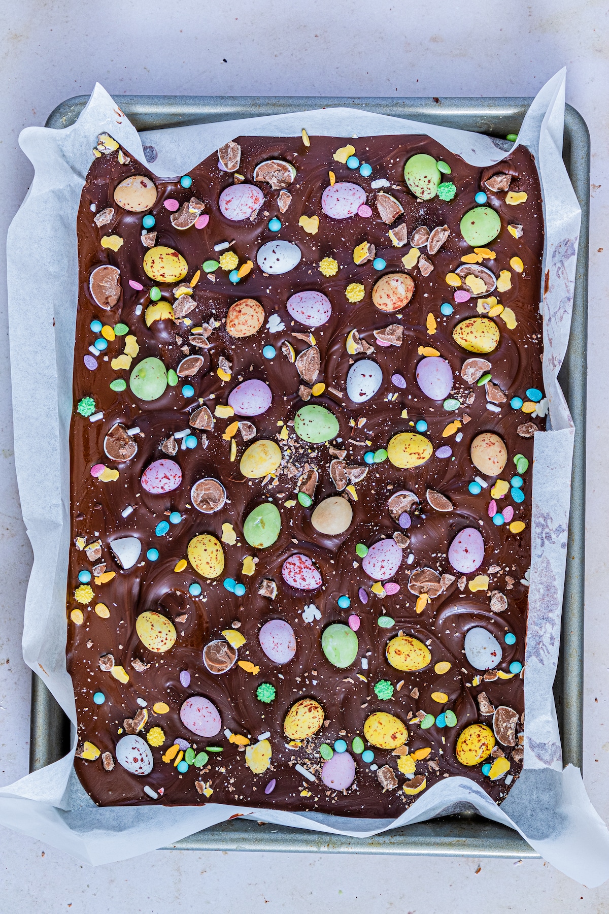 Overhead shot of easter candy bark on a parchment paper lined baking sheet to cool