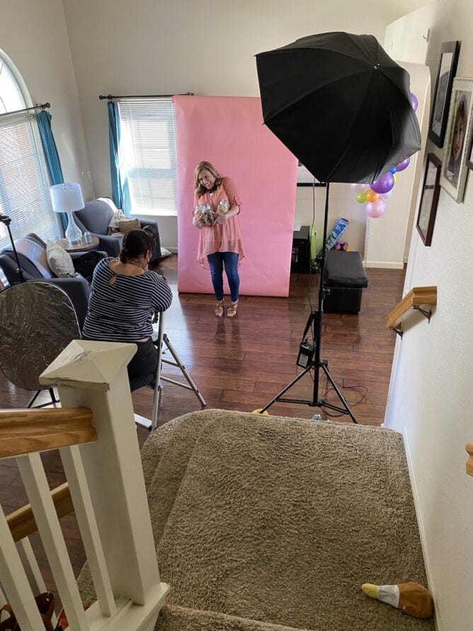 photographer taking picture of woman in pink shirt in front of pink background