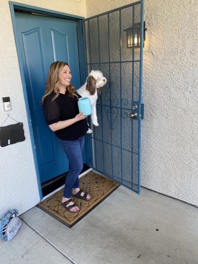 woman holding dog in from of blue front door