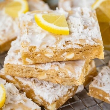 Stack of three lemon coconut blondies with a lemon slice on top