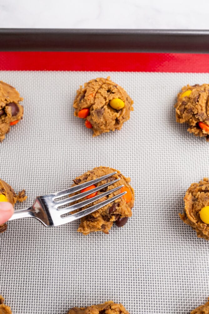 Overhead shot showing a fork pressing into cookie dough ball before baking