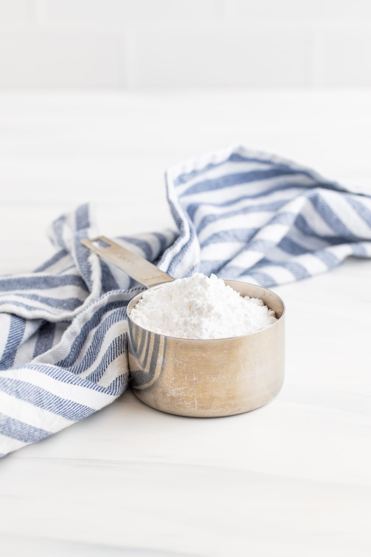 Stainless steel measuring cup full of powdered sugar