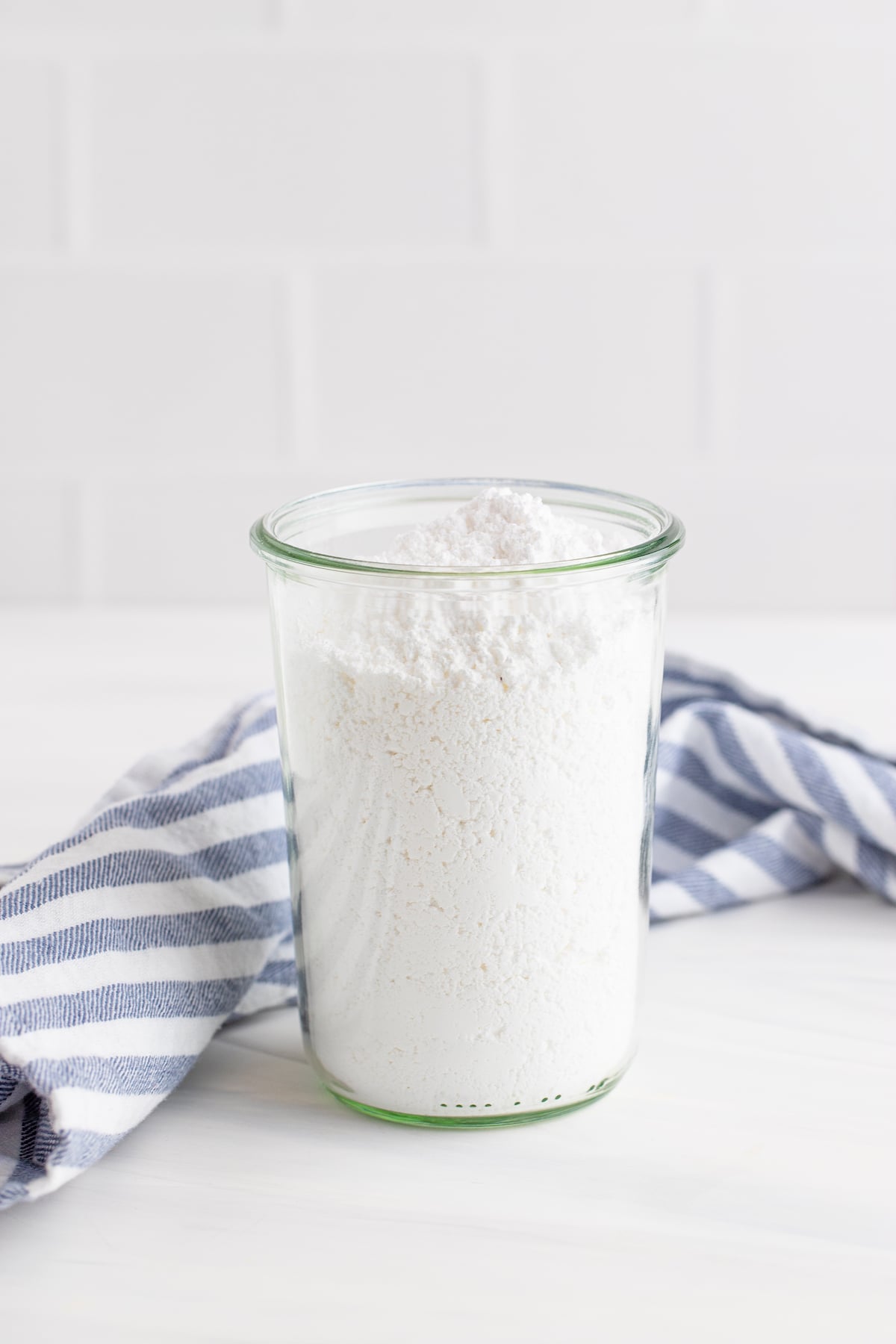 Side view of powdered sugar in a tall clear glass