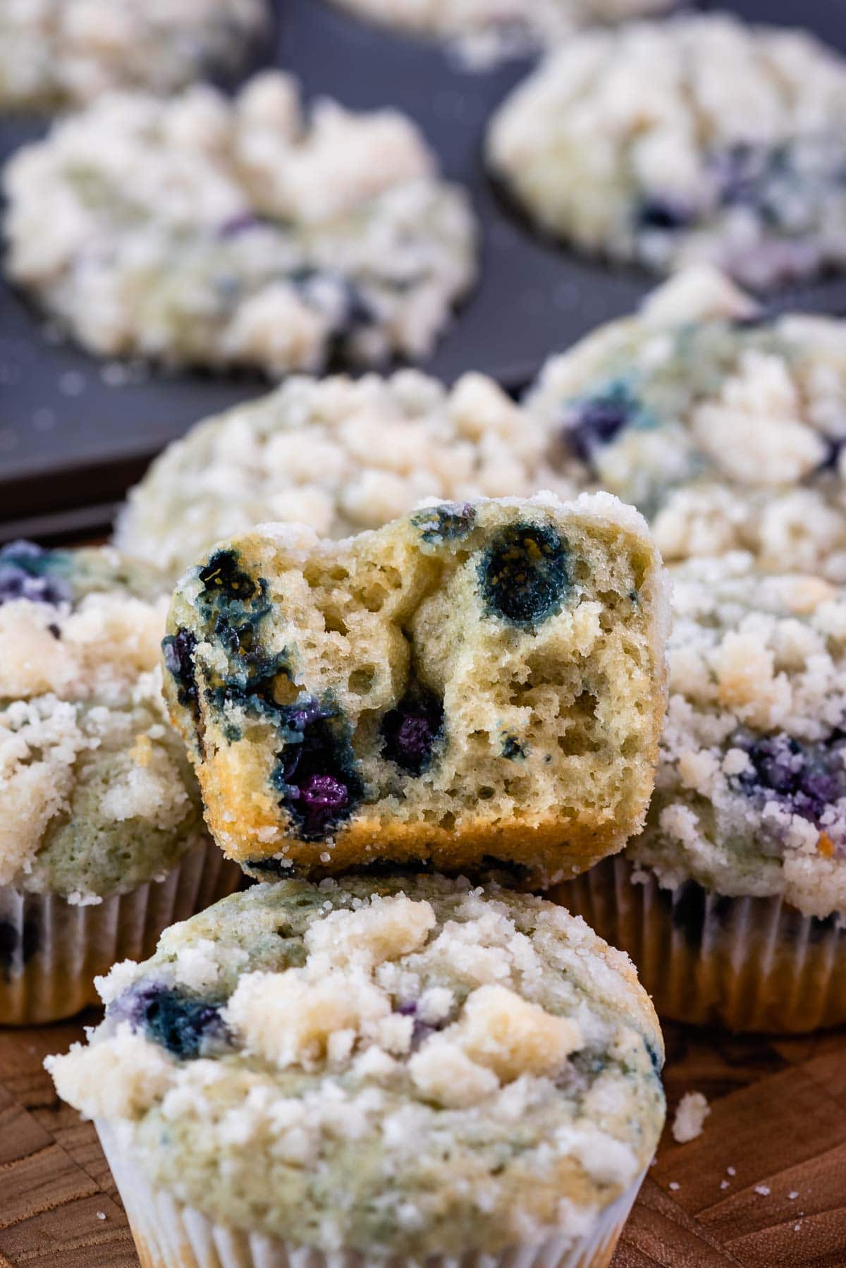 cut in half blueberry muffin sitting on stack of muffins