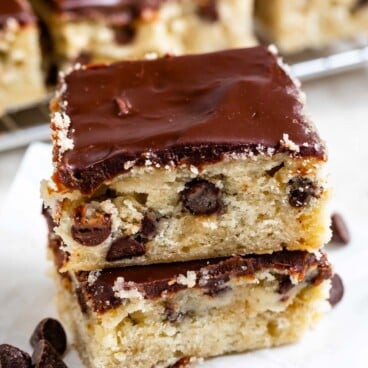 Two easy chocolate chip banana bars with chocolate ganache on top stacked on eachother with more bars in background