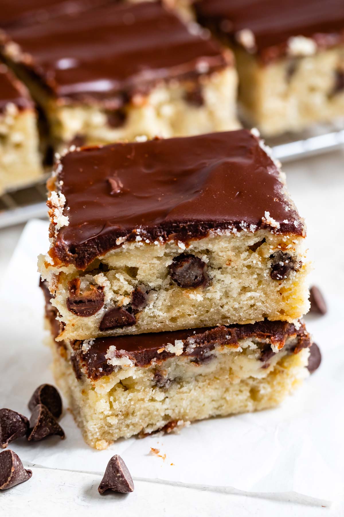 Two easy chocolate chip banana bars with chocolate ganache on top stacked on eachother with more bars in background