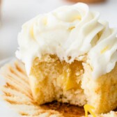 A perfect triple lemon cupcake cut in half to show lemon curd filling with recipe title on top of image