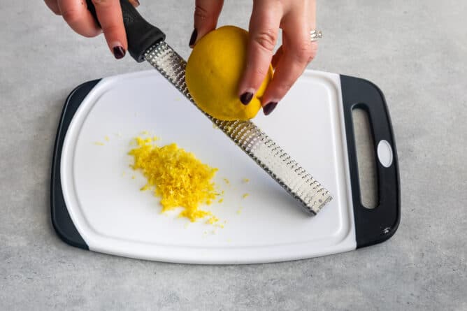 Overhead shot of lemon being zested over a cutting board