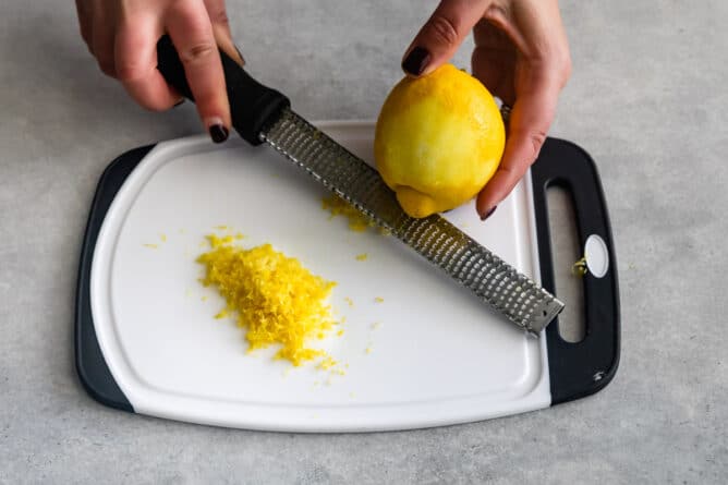 Overhead shot of lemon being zested over a cutting board