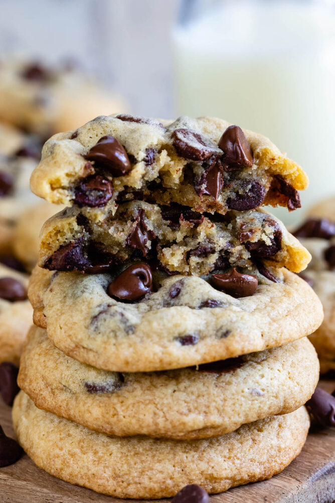 stack of 3 cookies with cookie cut in half on top with gooey chocolate chips