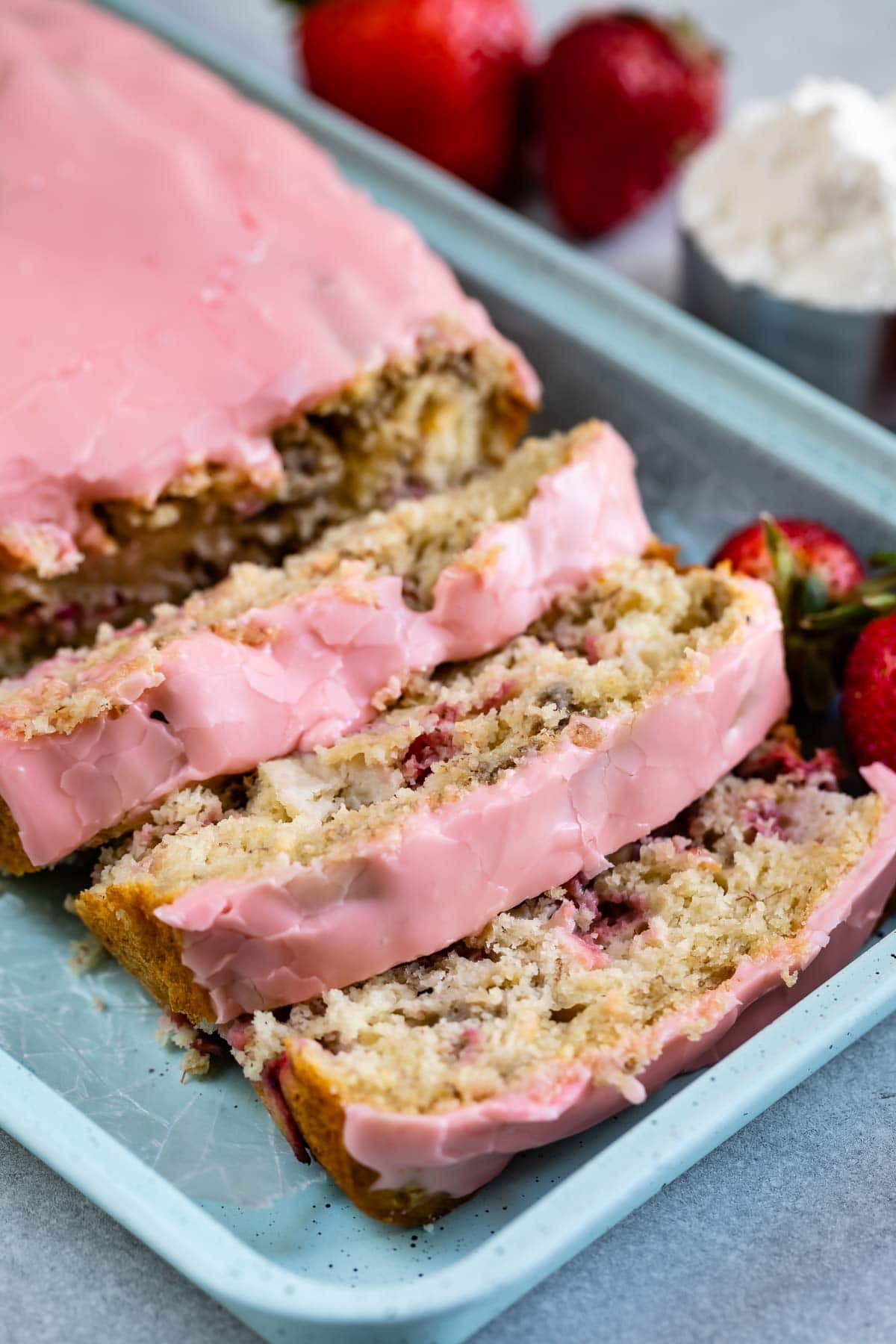 sliced quick bread with pink frosting on teal tray