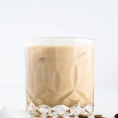 Side shot of white russian in a cocktail glass with coffee beans around it