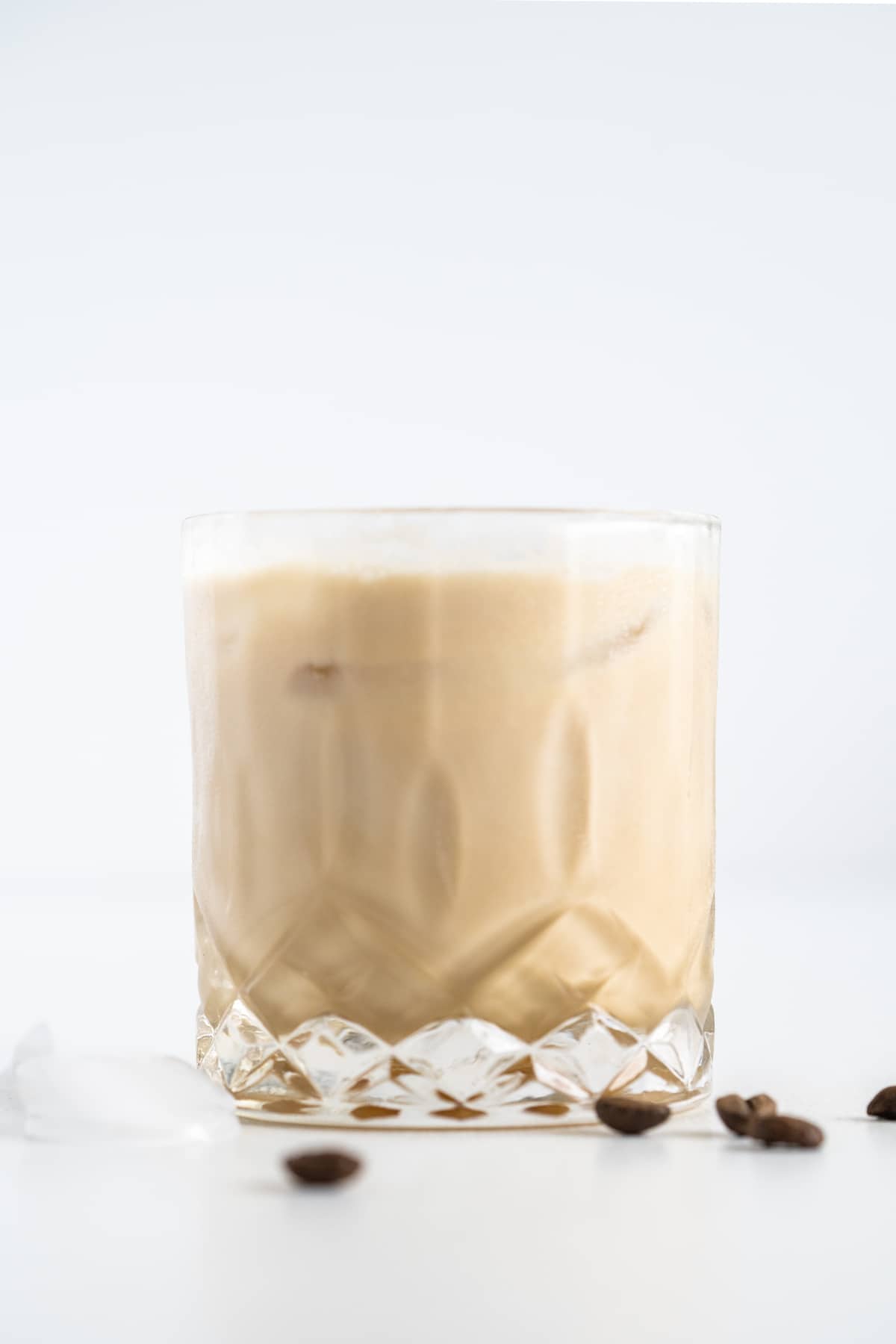 Side shot of white russian in a cocktail glass with coffee beans around it