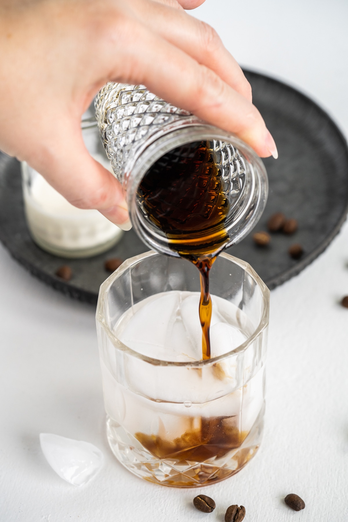 Coffee liqueur being poured into a cocktail glass to make white russian