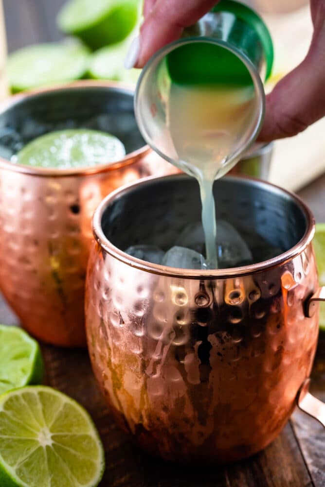 Lime juice being poured into a moscow mule mug