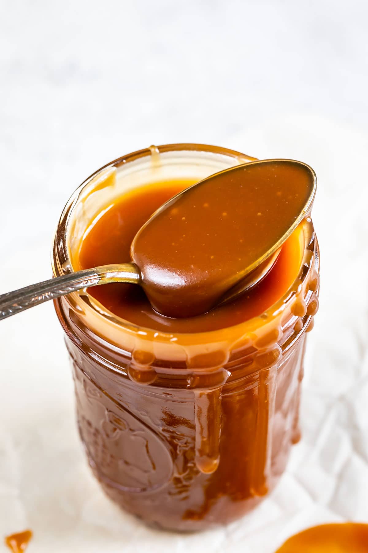 Spoonful of easy caramel sauce coming out of mason jar of sauce