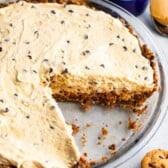 Close up overhead shot of chocolate chip peanut butter pie with one slice missing and chocolate chip cookies around the pie