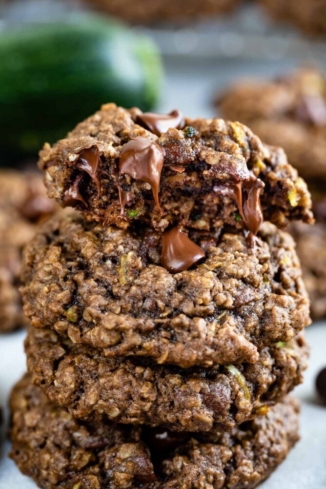 Chocolate zucchini oatmeal cookies stacked on eachother with top one split in half to show inside of cookie